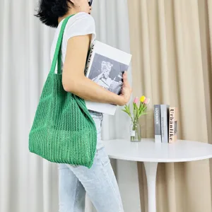 Green knitted hollow shoulder tote bag detail view, casual beach handbag texture display.