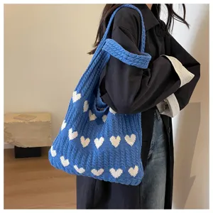 Detailansicht der blauen Strick-Tasche mit weißem Herzmuster und bequemen Schulterriemen.