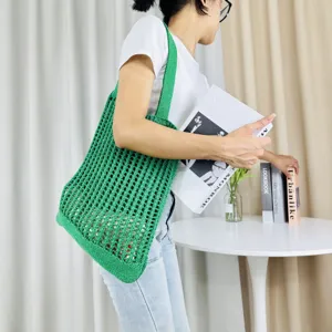 Detailaufnahme einer stilvollen grünen Strick-Schultertasche im Alltagsszenario gezeigt.