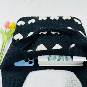 Schwarze Strick-Tragetasche Detail mit Herzmuster, geräumiger Innenraum mit Handy.