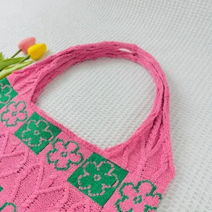 Close-up detail of pink knitted tote bag featuring green floral squares and soft texture.