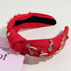 Detailed shot of a red knotted headband featuring sparkling rhinestones and cute heart charms.