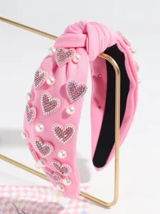 Pink knotted hair headband featuring sparkling rhinestone heart appliques and pearls for women.