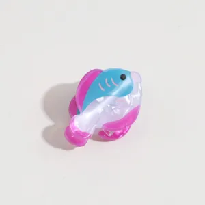 Gros plan détaillé de la jolie mini pince à cheveux en acétate en forme de poisson et texture.