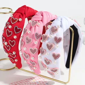 Stylish knotted headband with rhinestone hearts and faux pearls, perfect hair accessory main view.