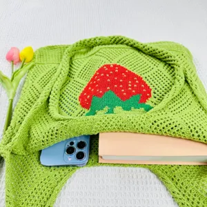 Nahaufnahme Detail der gruenen Stricktasche mit rotem Erdbeermuster und schoener Textur.