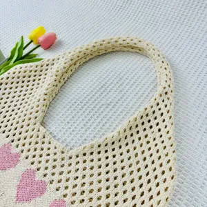 Detailansicht der beigen Strick-Netztasche mit süßen rosa Herzmustern, lässige Sommer-Strandtasche.