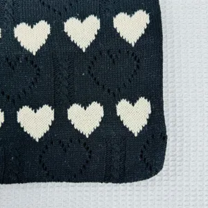 Schwarzes Strickgewebe Detail mit niedlichen weißen Herzen und feiner strukturierter Webung.