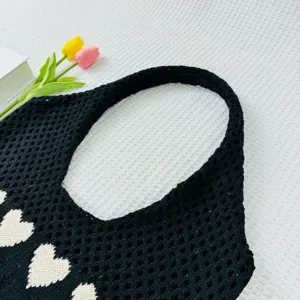 Nahaufnahme einer schwarzen Strick-Häkel-Tragetasche mit einem schönen weißen Herzmuster.