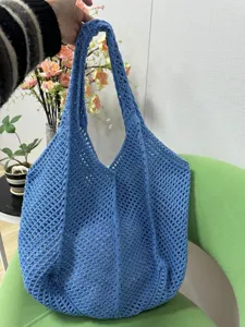 Detailansicht einer stilvollen blauen Häkel-Handtasche mit feiner Maschenstruktur und Griffen.