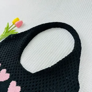 Nahaufnahme der schwarzen Strick-Tragetasche mit rosa Herzmuster, stylische Strandtasche.