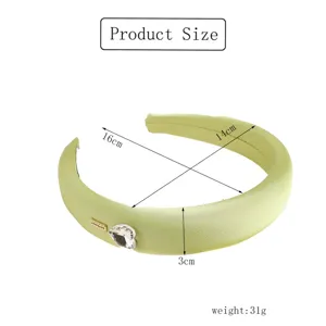 Dettaglio di cerchietto imbottito verde con cuore in cristallo e dimensioni precise del prodotto.