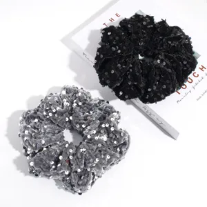 Detailed shot of large sequin hair scrunchies in black and grey, soft velvet fabric.