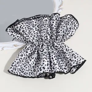 Close-up detail of a large black and white leopard print hair scrunchie with ruffled design.