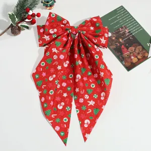 Détail de pince à cheveux nœud rouge de Noël, accessoire ruban imprimé festif.