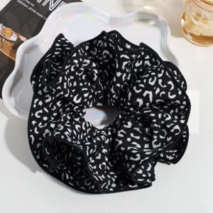 Detailed view of an oversized black and white leopard print hair scrunchie on a chic tray.
