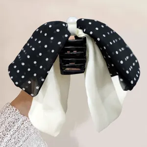 Close-up detail of a sweet black and white polka dot bow hair claw clip with elegant streamers.