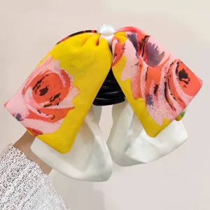 Detailed close-up of a sweet floral bow hair claw clip with pearl accent and fabric design.