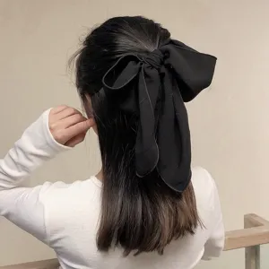 Vista detallada de una gran pinza para el cabello con lazo de satén negro, diseño elegante.