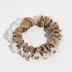 Detail shot of the brown satin scrunchie featuring elegant white lace ruffle trim texture.