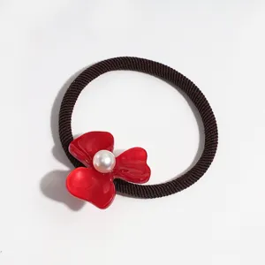 Detailed shot of the red acetate flower hair tie with a faux pearl center, ponytail holder.