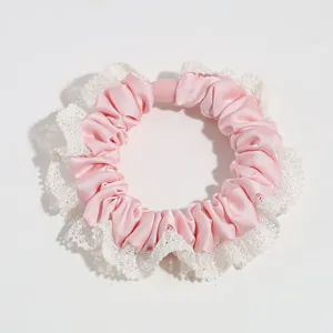 Detailed close-up of sweet pink satin hair scrunchie with elegant white lace trim design.