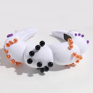 Close-up detail of white padded headband decorated with colorful faux pearls for parties.