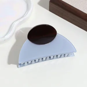 Primo piano dettagliato della molletta per capelli in acetato con design bicolore.