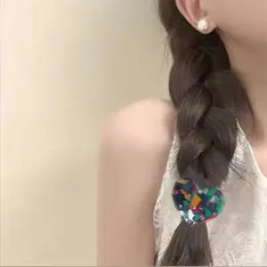 Detailed view of a fashionable heart-shaped acetate hair tie with colorful rhinestones