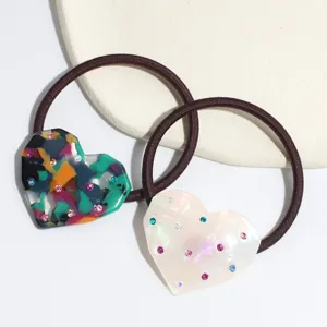 Close-up of heart-shaped acetate hair ties with colorful rhinestones and elastic bands.