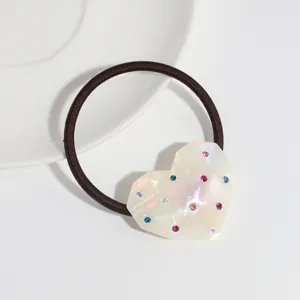 Detail view of a minimalist heart-shaped resin hair tie featuring colorful crystal rhinestones.