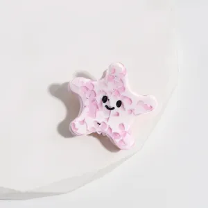 Gros plan d'une jolie pince à cheveux étoile de mer rose en acétate, accessoire doux.