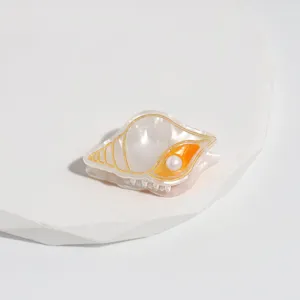 Vue détaillée d'une pince à cheveux coquillage perle, accessorio acétate mini coiffure.