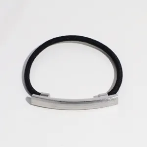 Gros plan d'un élastique à cheveux noir minimaliste avec un accessoire de barre métallique incurvée.