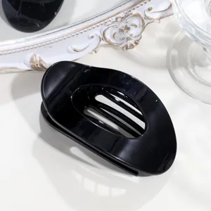 Detailaufnahme einer eleganten schwarzen ovalen Haarklammer, minimalistisches Haaraccessoire.