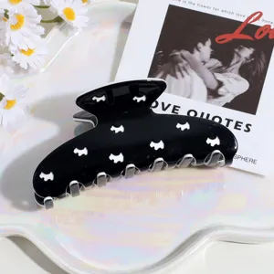 Primer plano detallado de una elegante pinza para el cabello negra con siluetas de perros.