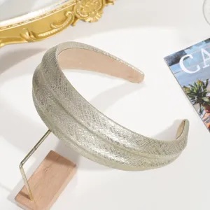 Vista detallada de diadema ancha de cuero con serpiente, textura metálica brillante.
