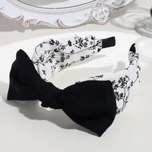 Close-up detail of the black and white floral headband with a chic bowknot and wide design.