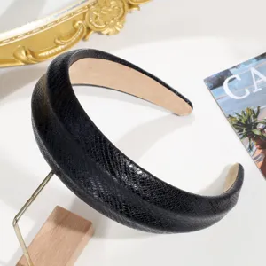 Primer plano detallado de una elegante diadema ancha de piel de serpiente negra.