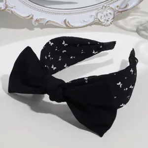 Black wide headband with large bow and cute white butterfly print detail for women hair styling.