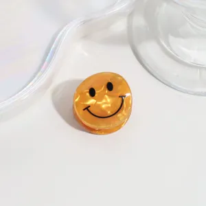 Close-up of cute mini amber acrylic smiley face hair claw clip, clear detail view.