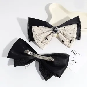 Bonita pinza de pelo de lazo en blanco y negro con diamantes de imitación y cierre de resorte.
