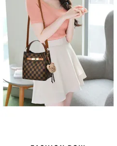 Vue détaillée du sac seau chic à motif quadrillé avec un charmant pendentif ours.
