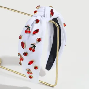 Detailansicht eines eleganten weißen Haarreifs mit roten Strasssteinen und Kirschen.