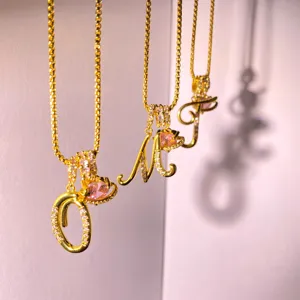 Gold letter pendant necklace with pink crystal orb design, stylish clavicle chain jewelry.