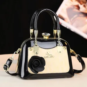 Vista dettagliata della borsa nera lucida e beige con dettagli dorati e decorazione floreale.