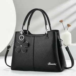 Borsa a mano nera in pelle sintetica con ciondolo a fiore e dettagli in metallo.