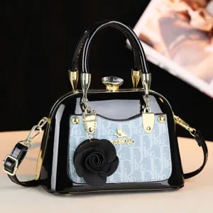 Borsa a mano in pelle verniciata nera con tasca monogram blu, dettagli dorati e chiusura in cristallo.