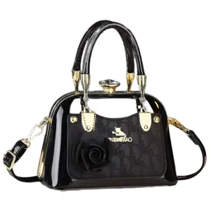 Elegante borsa a mano in pelle verniciata nera con dettagli dorati e ciondolo floreale.