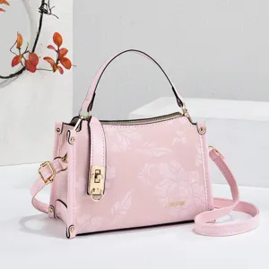 Pink floral embossed mini top-handle handbag with lock closure and crossbody strap for women.